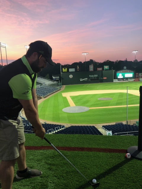 Dana golfing at a baseball field in Voraus hat and polo